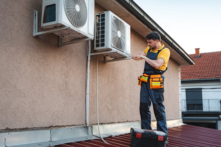 HVAC technician installing an air conditioner on the wall of a house